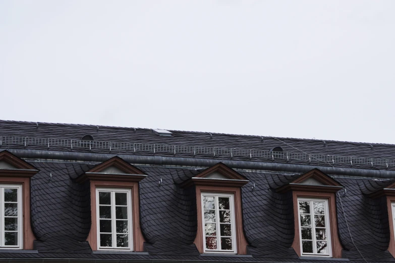 a clock that is on the side of a building, pexels contest winner, postminimalism, gambrel roof building, detmold, window ( rain ), black and terracotta