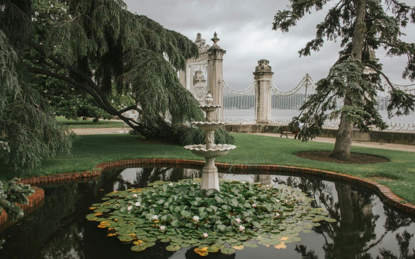 a pond with water lilies and a bridge in the background, a marble sculpture, inspired by Serafino De Tivoli, pexels contest winner, neoclassicism, fountain in the middle, castelvania, bay area, ornate with diamonds