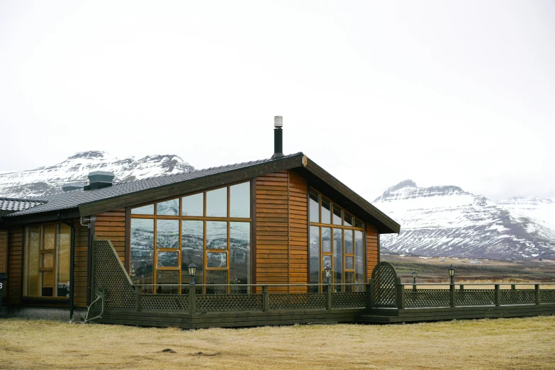 a house in the middle of a field with mountains in the background, by Hallsteinn Sigurðsson, hurufiyya, large green glass windows, restaurant, exterior photo