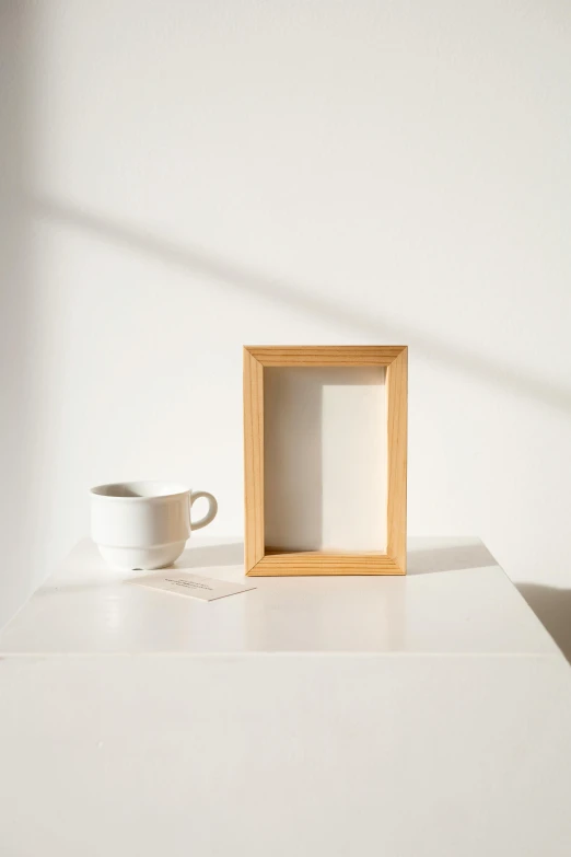 a picture frame sitting on top of a table next to a cup, visual art, oak, set against a white background, display item, multiple stories