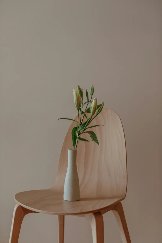 a white vase sitting on top of a wooden chair, inspired by Constantin Hansen, unsplash, lily, ignant, tall flowers, longque chen