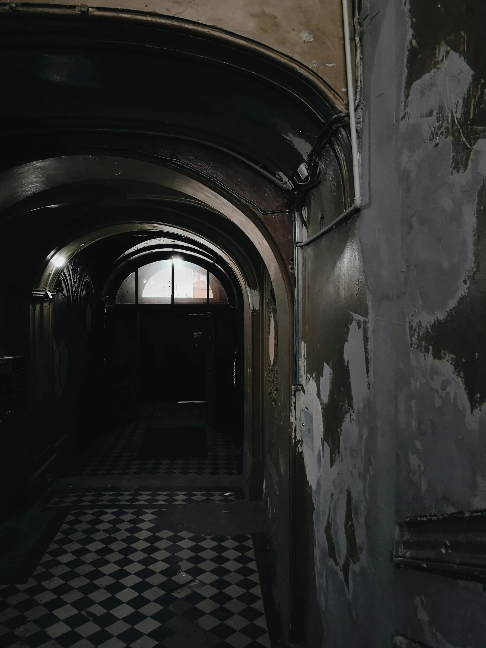 a dark hallway with a black and white checkered floor, pexels contest winner, an old abandoned mansion, archs and walls, low quality photo, photo for a magazine