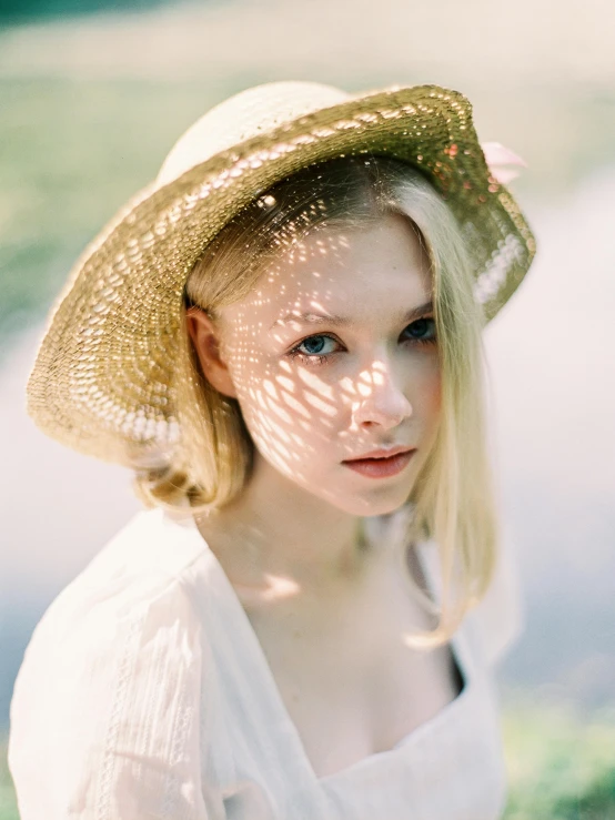 a close up of a person wearing a hat, by Anna Boch, unsplash, renaissance, blonde beautiful young woman, dappled light, portra, low quality photo