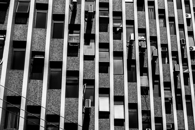 a black and white photo of a tall building, a photo, inspired by André Kertész, pexels contest winner, brutalism, air conditioner, melbourne, broken windows, shot on 1 5 0 mm