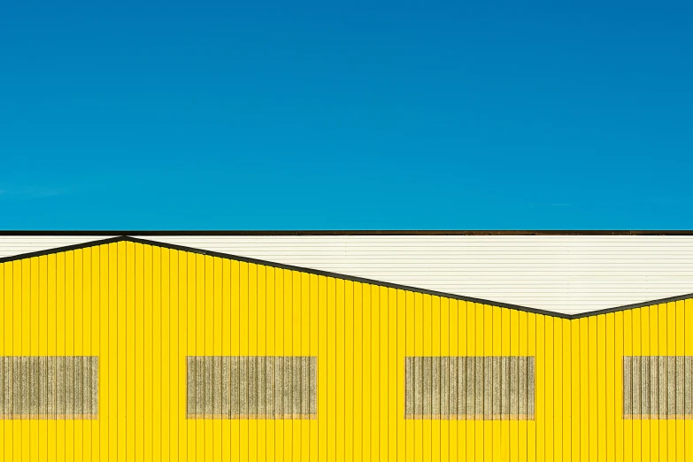 a yellow building with a blue sky in the background, a minimalist painting, by Matthias Weischer, unsplash contest winner, shed roof, ffffound, hangar, abstract composition