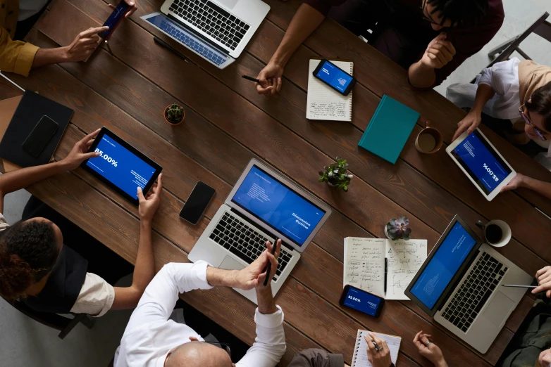 a group of people sitting around a table with laptops, by Carey Morris, pexels contest winner, 9 9 designs, teaser, rectangle, on a desk