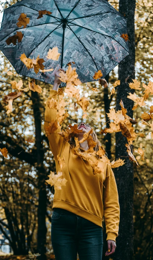 a woman holding an umbrella in the air, by Carey Morris, pexels contest winner, made of leaves, scattered golden flakes, 15081959 21121991 01012000 4k, thumbnail