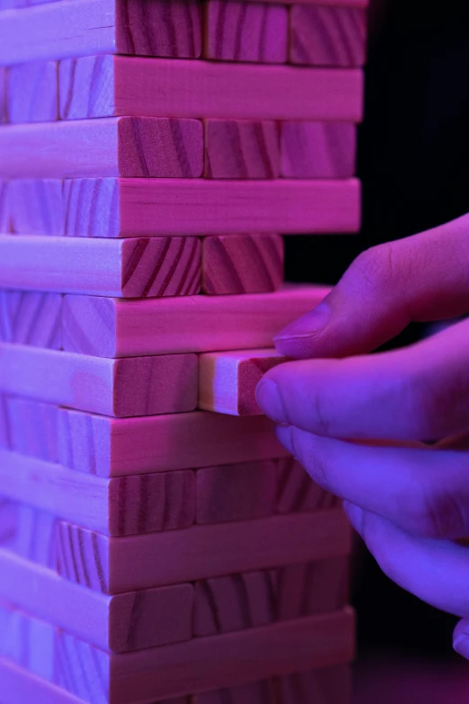 a person playing a game with wooden blocks, by Greg Rutkowski, unsplash, interactive art, pink violet light, twisted giant tower, close - up on detailed, hyperrealistic