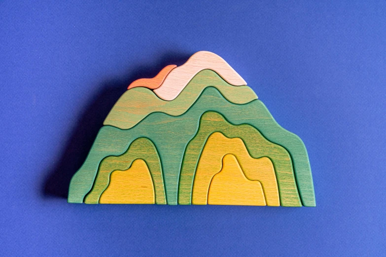 a wooden mountain is shown against a blue background, a jigsaw puzzle, by Andrée Ruellan, painted pale yellow and green, sundown, cascading, high view