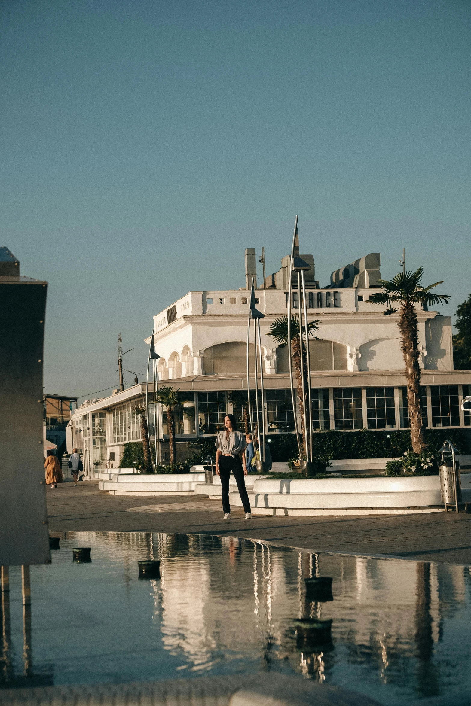 a man riding a skateboard down the side of a street, unsplash, modernism, docked at harbor, cannes, art deco architecture, standing on the water ground