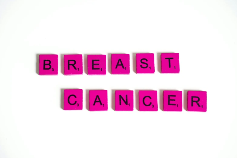pink blocks spelling breast cancer on a white surface, a photo, by Juliette Wytsman, pixabay, 3/4 bust, breathing, cmyk, nut