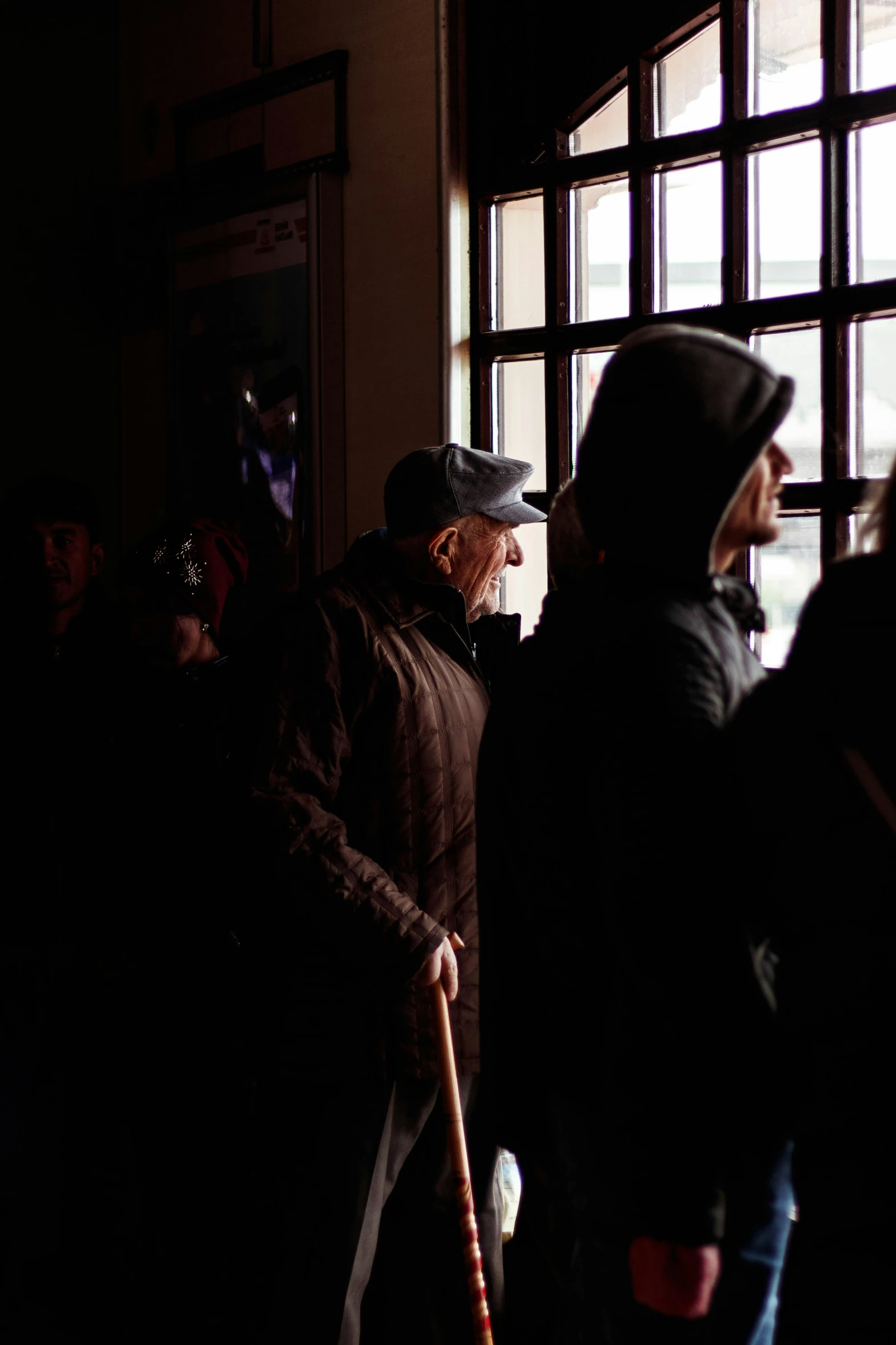 a group of people standing in front of a window, inside berghain, in line, cold lighting, documentary