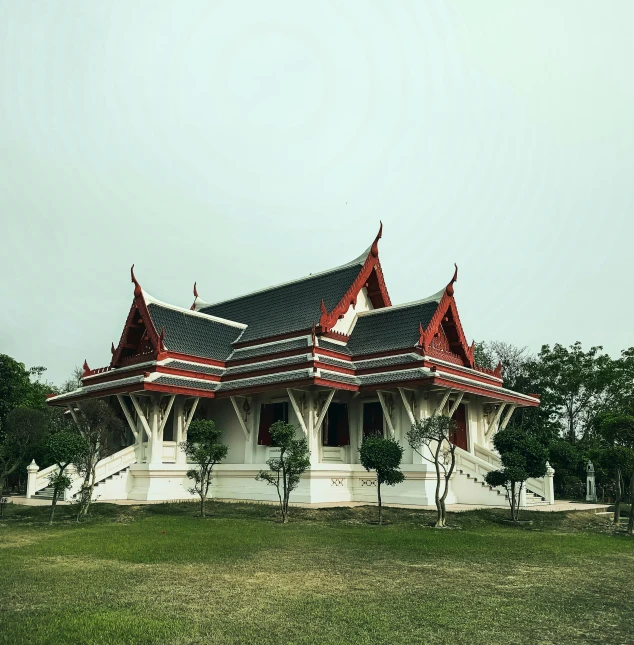 a red and white building sitting on top of a lush green field, a colorized photo, pexels contest winner, minimalism, thai temple, cyberpunk temple, nice slight overcast weather, album