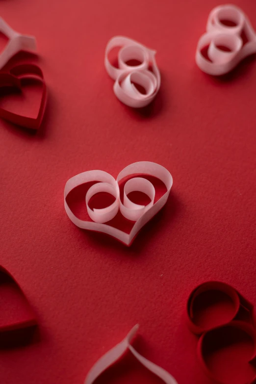 a bunch of paper hearts on a red surface, pexels, spiralling, satin ribbons, love scene, paul barson