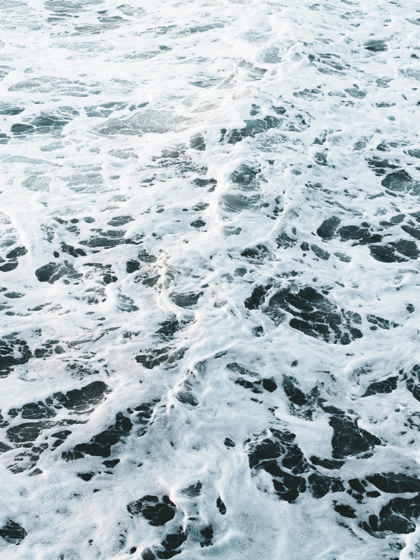 a man riding a surfboard on top of a wave covered beach, inspired by Vija Celmins, trending on unsplash, renaissance, on a yacht at sea, full frame image, oil on water, in the iceland calm water