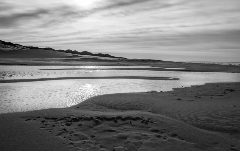 a black and white photo of a beach, inspired by Edward Weston, winding rivers, sunrise light, uploaded, dessert