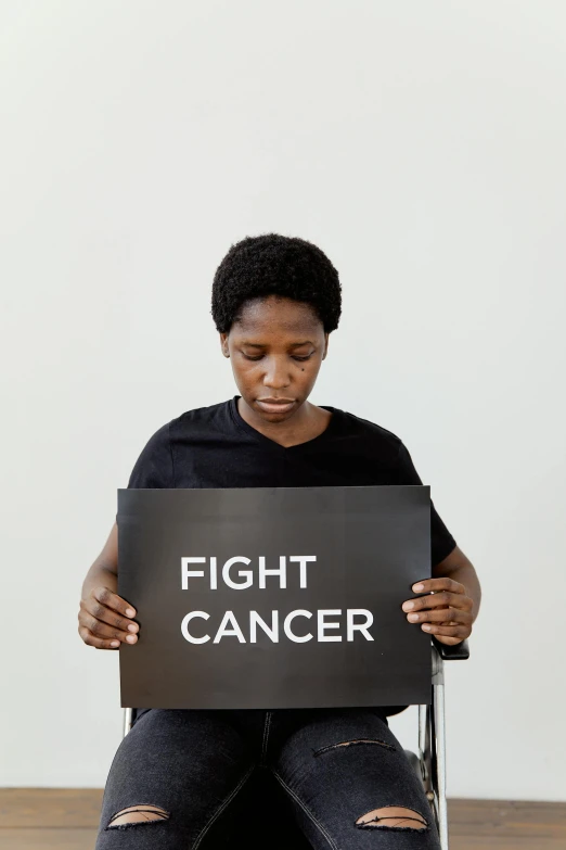 a woman sitting in a chair holding a sign that says fight cancer, pexels contest winner, renaissance, man is with black skin, fighting stance energy, profile image, instagram picture