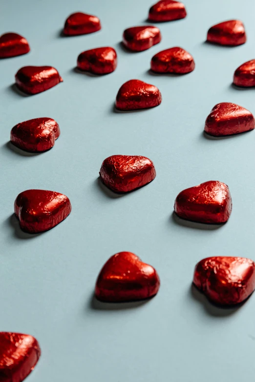 a table topped with lots of red chocolate hearts, an album cover, pexels, teal silver red, hegre, sunlit, in a row