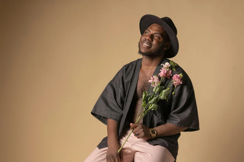 a man sitting on a stool holding a flower, an album cover, inspired by Theo Constanté, pexels contest winner, figuration libre, kevin hart, holding flowers, he is wearing a hat, blushing