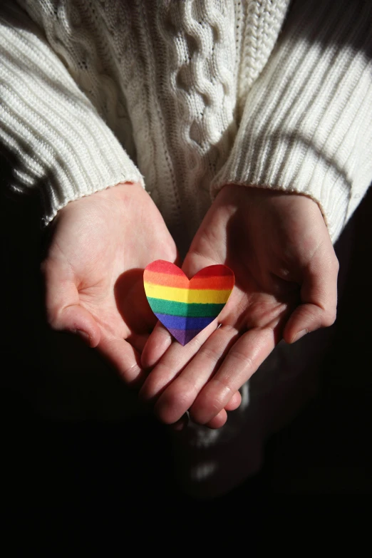 a person holding a rainbow heart in their hands, trending on pexels, androgynous, photograph credit: ap, multiple stories, family photo