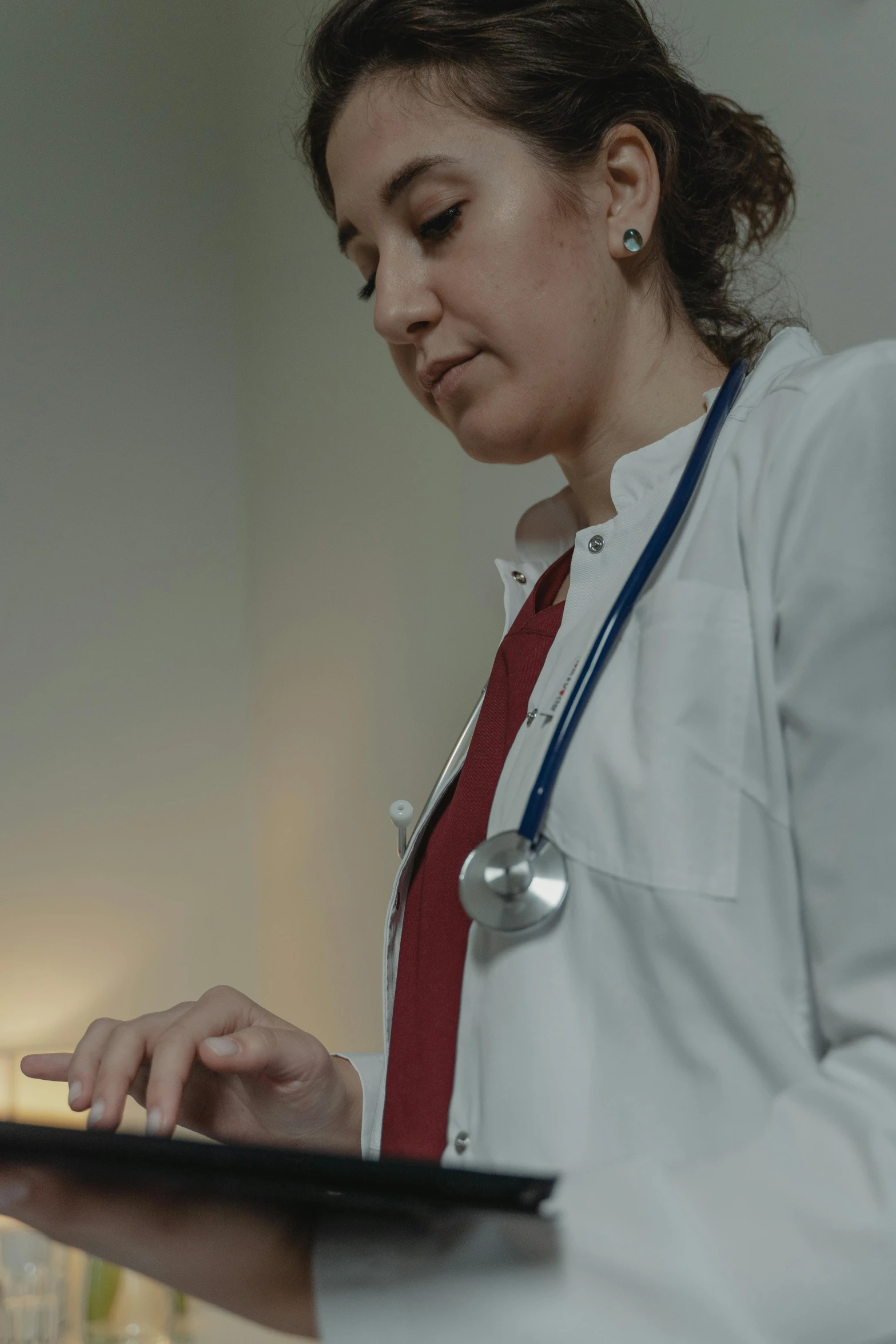 a woman in a lab coat using a laptop, a colorized photo, by Adam Marczyński, pexels, with a stethoscope, gif, cas