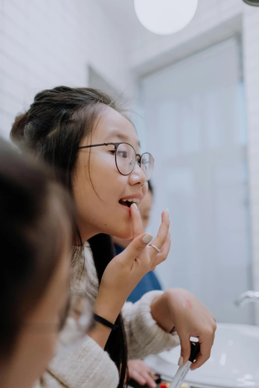 a woman brushing her teeth in front of a mirror, inspired by Feng Zhu, pexels contest winner, academic art, in a school classroom, wearing square glasses, teenage girl, asian descent