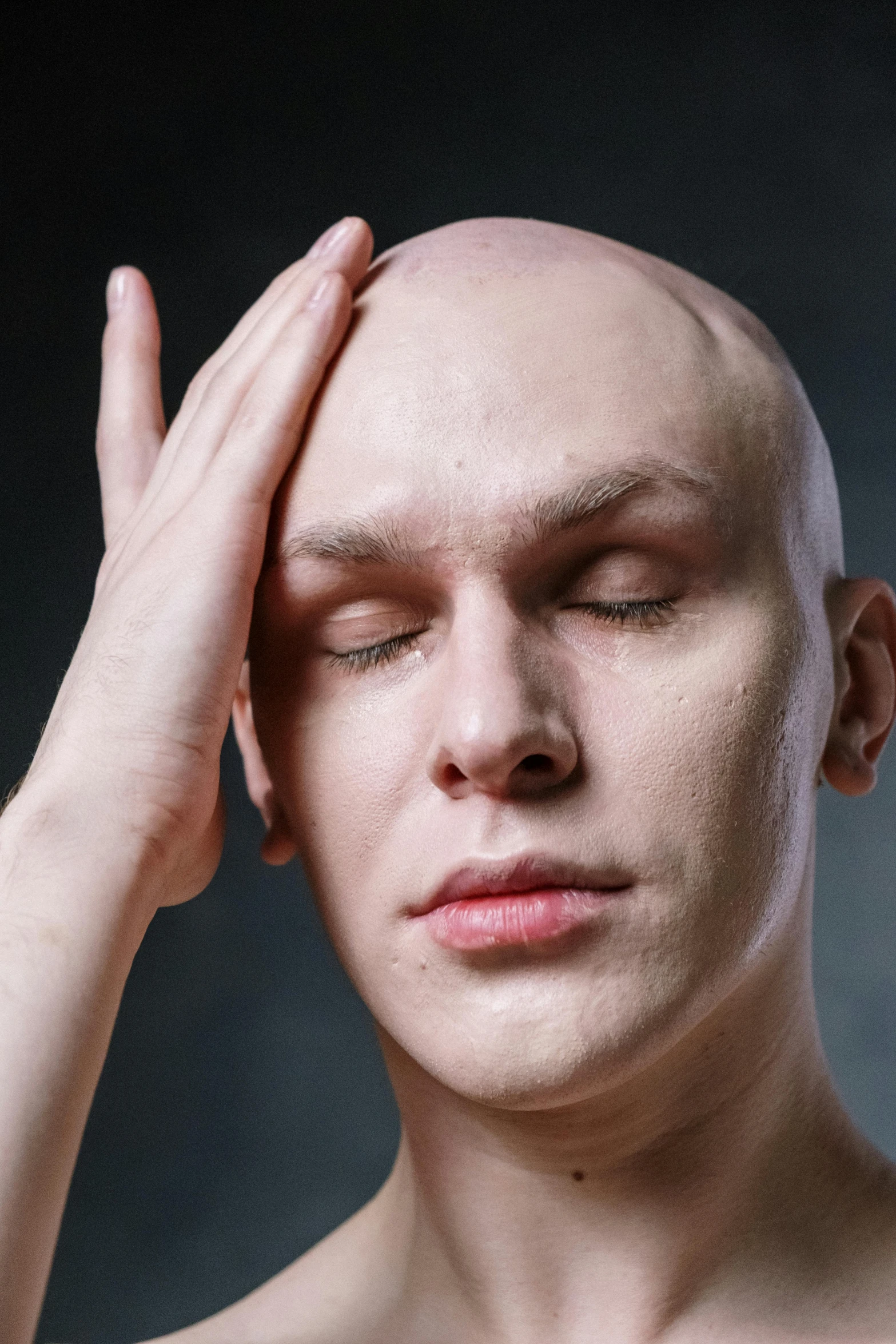 a man with a bald head is holding his hands to his head, an album cover, inspired by Odd Nerdrum, shutterstock, albino skin, sleepy fashion model face, linus from linustechtips, headshot profile picture