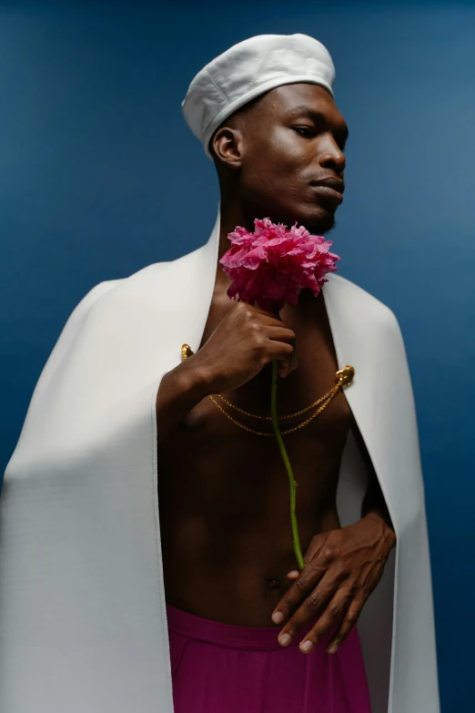 a man in a white robe holding a pink flower, an album cover, inspired by Barthélemy Menn, trending on pexels, afrofuturism, disrobed, an epic non - binary model, wearing a king's cape, photographed for reuters