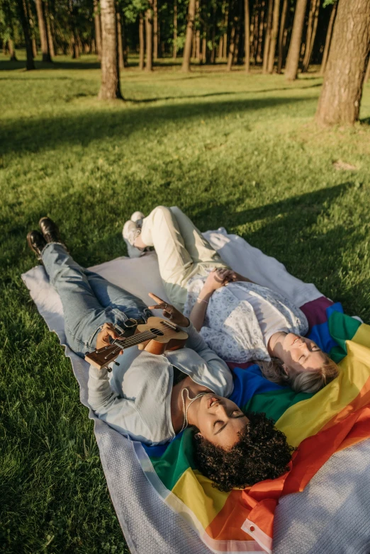 a couple of people laying on top of a blanket, trending on pexels, gay pride, at a park, instagram post, lesbian