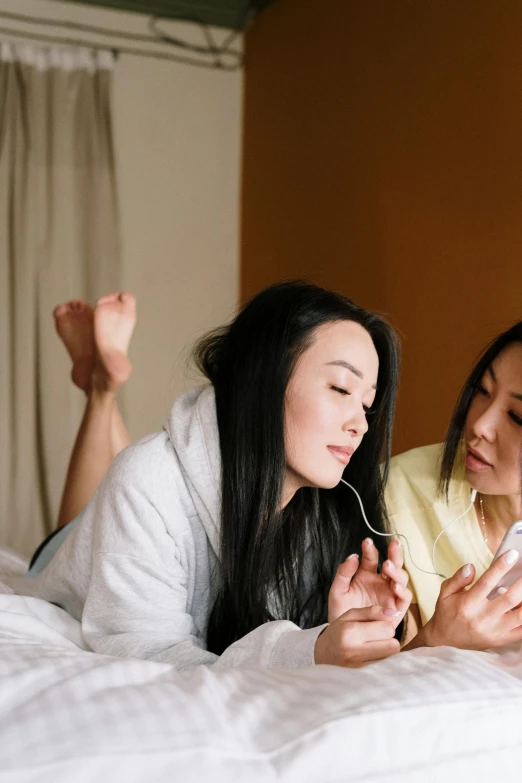 a couple of women laying on top of a bed, by Fei Danxu, trending on pexels, talking, half asian, gif, iphone