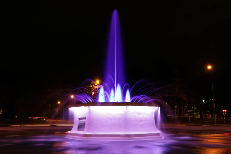 a blue fountain is lit up at night, by Cherryl Fountain, caulfield, glowing purple, album