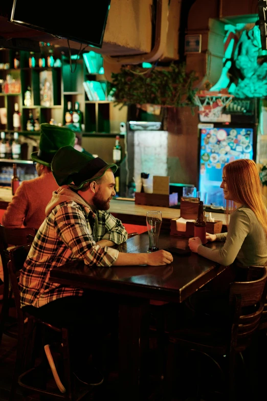 a couple of people that are sitting at a table, sitting alone at a bar, talking