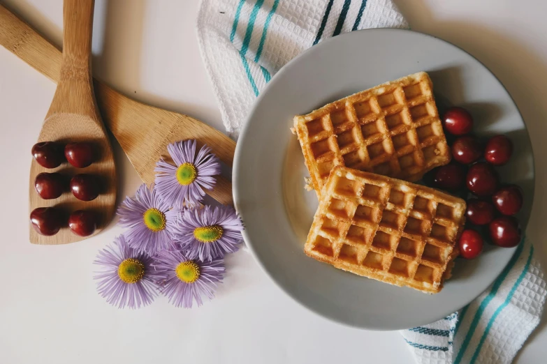 a white plate topped with waffles and cherries, a still life, by Carey Morris, pexels contest winner, sustainable materials, flower power, background image, a pair of ribbed