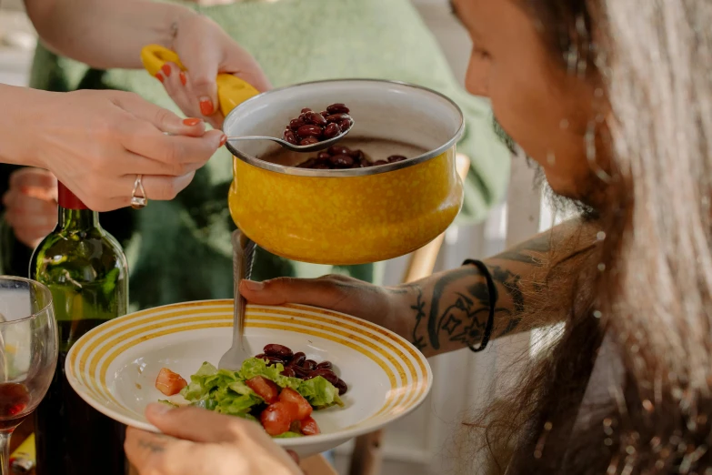 a group of people standing around a table with plates of food, by Emma Andijewska, pexels contest winner, process art, in a red dish, cottagecore hippie, soup, about to consume you