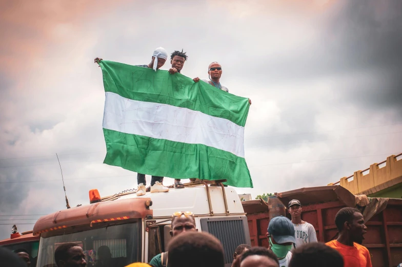 a group of people standing on top of a truck, trending on unsplash, green flag, orisha, square, community celebration