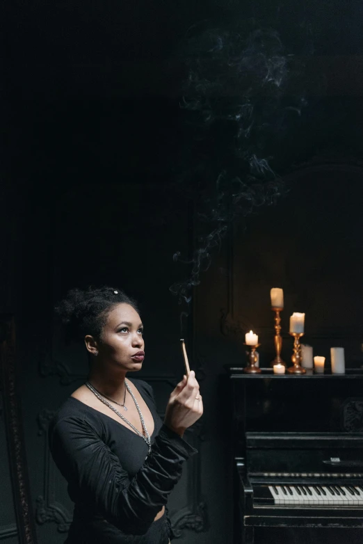 a woman standing in front of a piano smoking a cigarette, a portrait, inspired by Carrie Mae Weems, pexels contest winner, renaissance, beautiful witch spooky female, dark. studio lighting, holding a candle, subject action: smoking a cigar