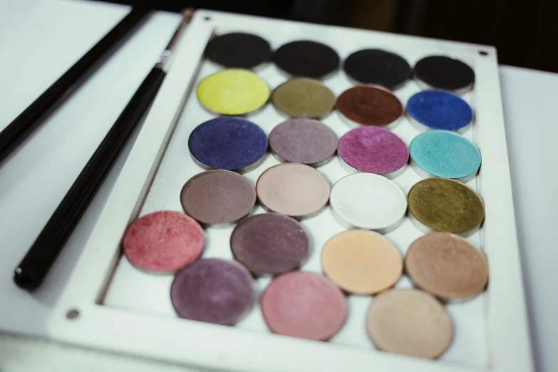 a palette sitting on top of a table next to a pair of chopsticks, inspired by Mac Conner, perfect colorful eyeshadows, industrial colours, hand - tinted, round shapes