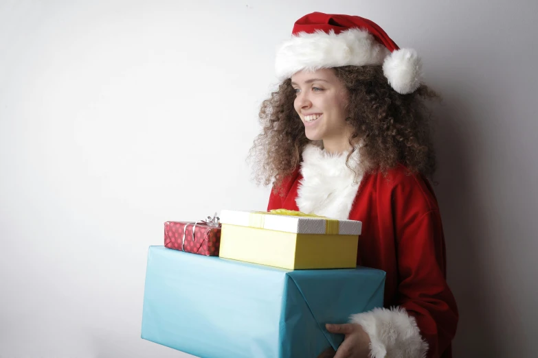 a woman in a santa hat holding a bunch of presents, by Alice Mason, pexels, curly haired, avatar image, teenager, full product shot