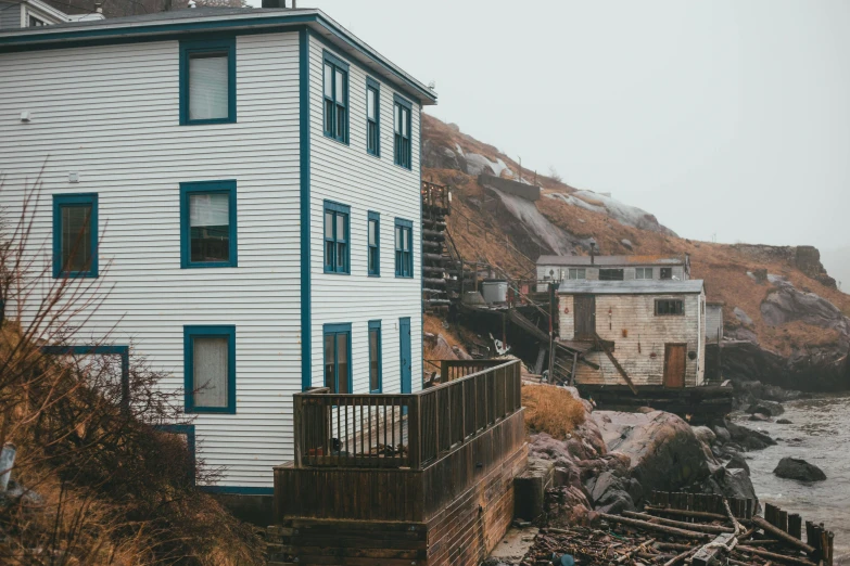 a house sitting on top of a cliff next to a body of water, by Carey Morris, pexels contest winner, collapsed buildings, mining outpost, seaside victorian building, gauthier leblanc