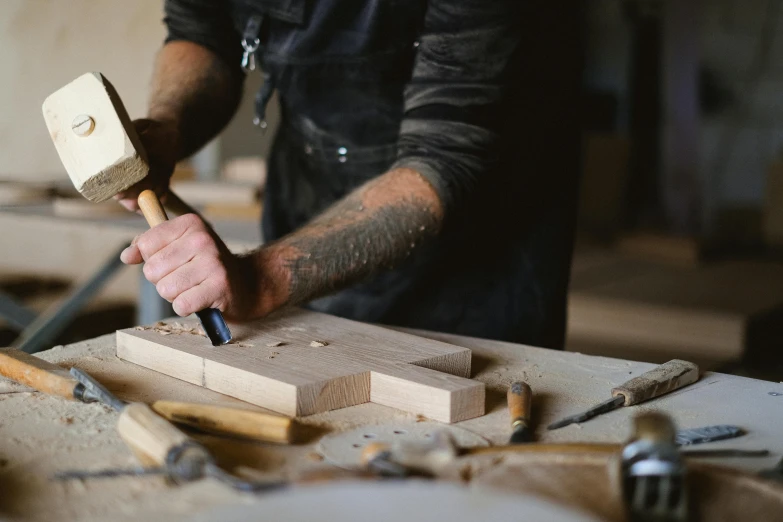 a man working on a piece of wood with a hammer, by Jessie Algie, trending on pexels, arts and crafts movement, 9 9 designs, rectangle, bespoke, multi-part