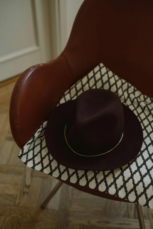 a brown hat sitting on top of a brown chair, featuring rhodium wires, authentic, felt, reclining