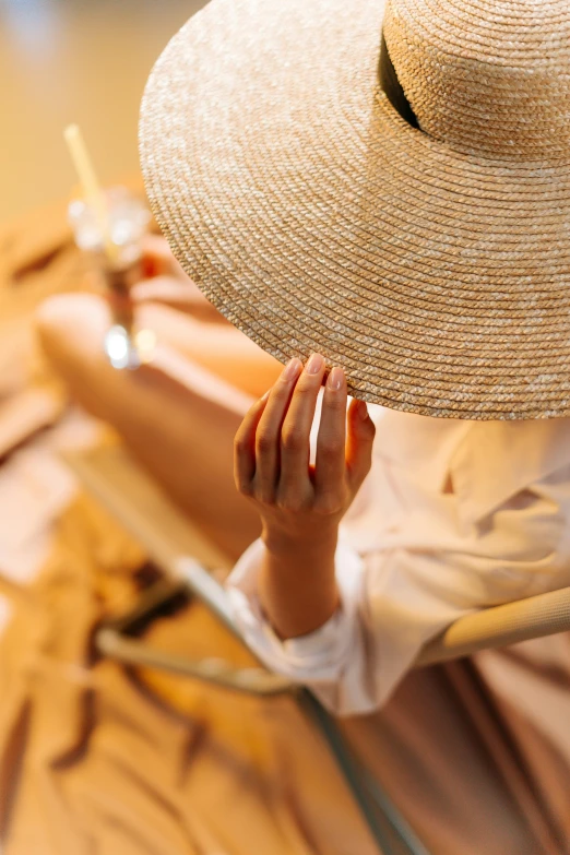 a woman sitting in a chair with a hat on, pexels contest winner, renaissance, deep tan skin, summer evening, hand holding cap brim, straw