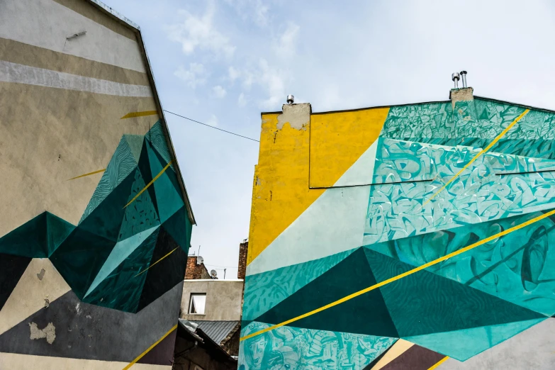 a colorful mural on the side of a building, by NEVERCREW, pexels contest winner, street art, gold and teal color scheme, geometric lines in the sky, andrée wallin, prussian blue and azo yellow