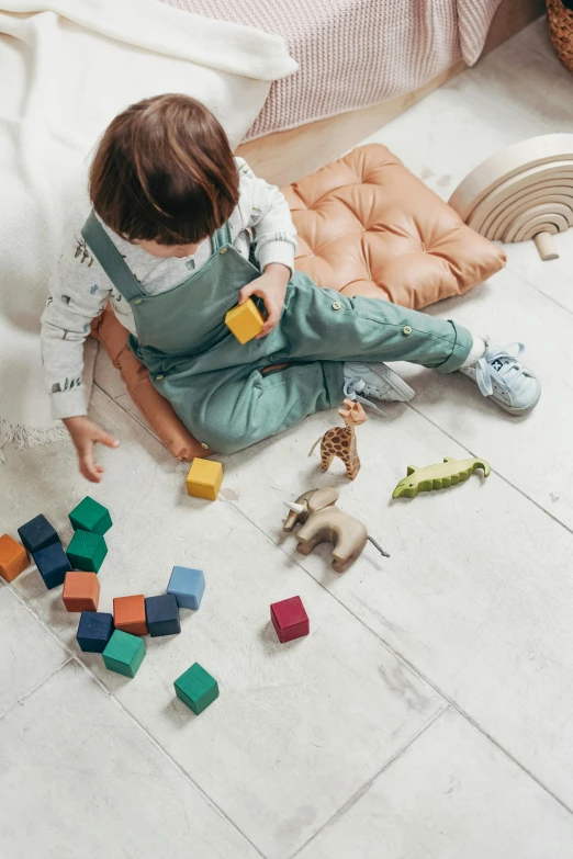 a little girl sitting on the floor playing with blocks, pexels, square, curated collections, grey, a green