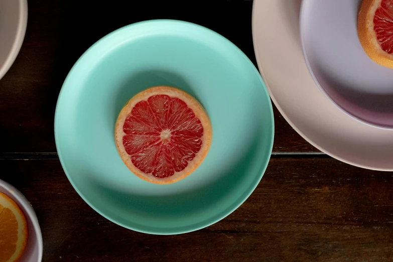 a grapefruit cut in half on a plate, a still life, inspired by Damien Hirst, unsplash, turquoise and venetian red, thin porcelain, 7 0 mm entrance pupil diameter, green and pink