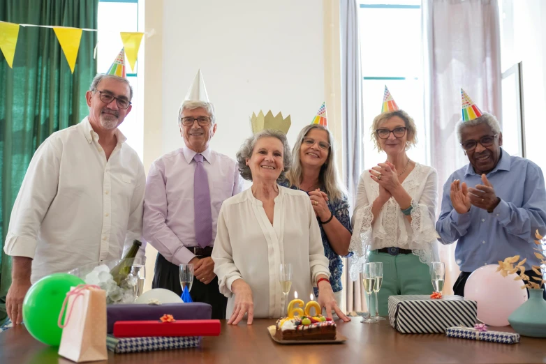 a group of people standing around a table, wearing a party hat, 7 0 years old, giorgia meloni, gourmet and crafts