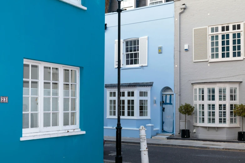 a red fire hydrant sitting on the side of a road, inspired by Rachel Whiteread, pexels contest winner, postminimalism, cyan shutters on windows, white houses, staggered terraces, hartper's bazaar