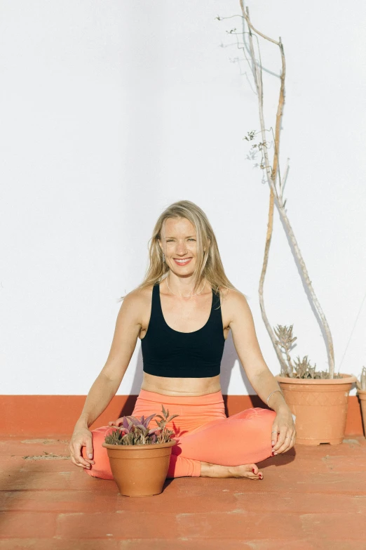 a woman sitting on the ground in front of a potted plant, yoga, terracotta, profile image, marbella