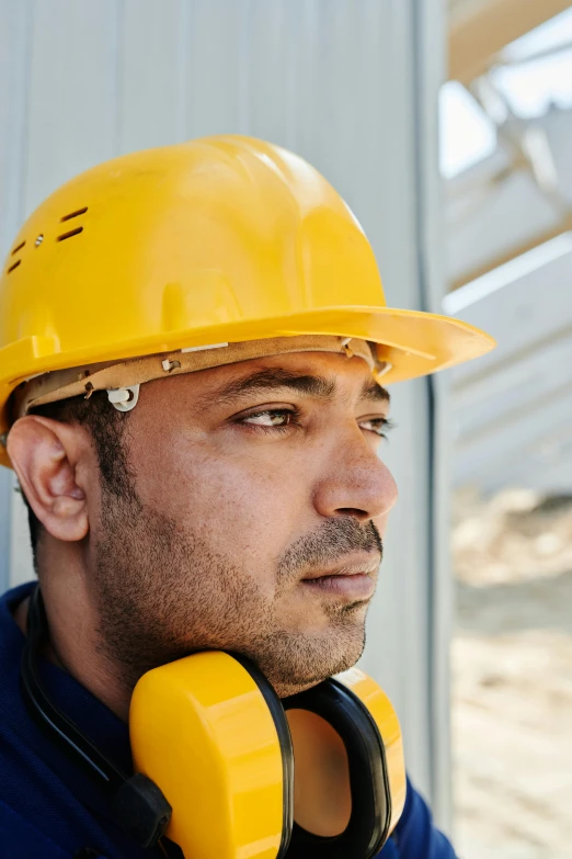 a man wearing a hard hat and headphones, inspired by Afewerk Tekle, thoughtful, bright construction materials, zoomed in, rugged details