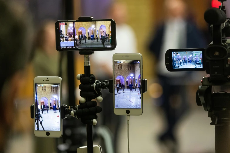 a group of cell phones sitting on top of a tripod, a picture, by Michael Goldberg, shutterstock, video art, live broadcast, photograph credit: ap, g 7 summit press photos, table with microphones